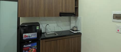 A compact kitchen with wooden cabinets, a black refrigerator, a sink, and a small countertop.