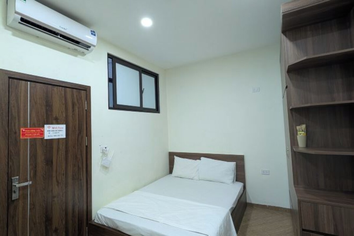 Una habitación de hotel con cama, armario de madera y unidad de aire acondicionado.