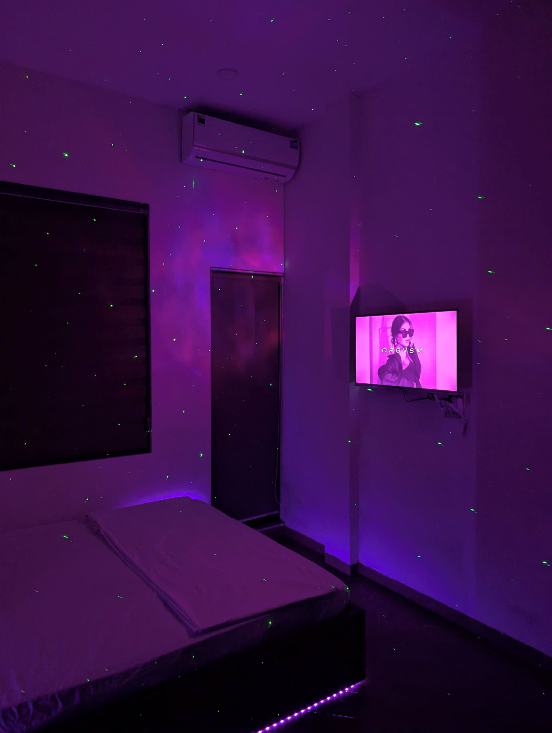 Una stanza con un letto, una televisione appesa al muro e una finestra.