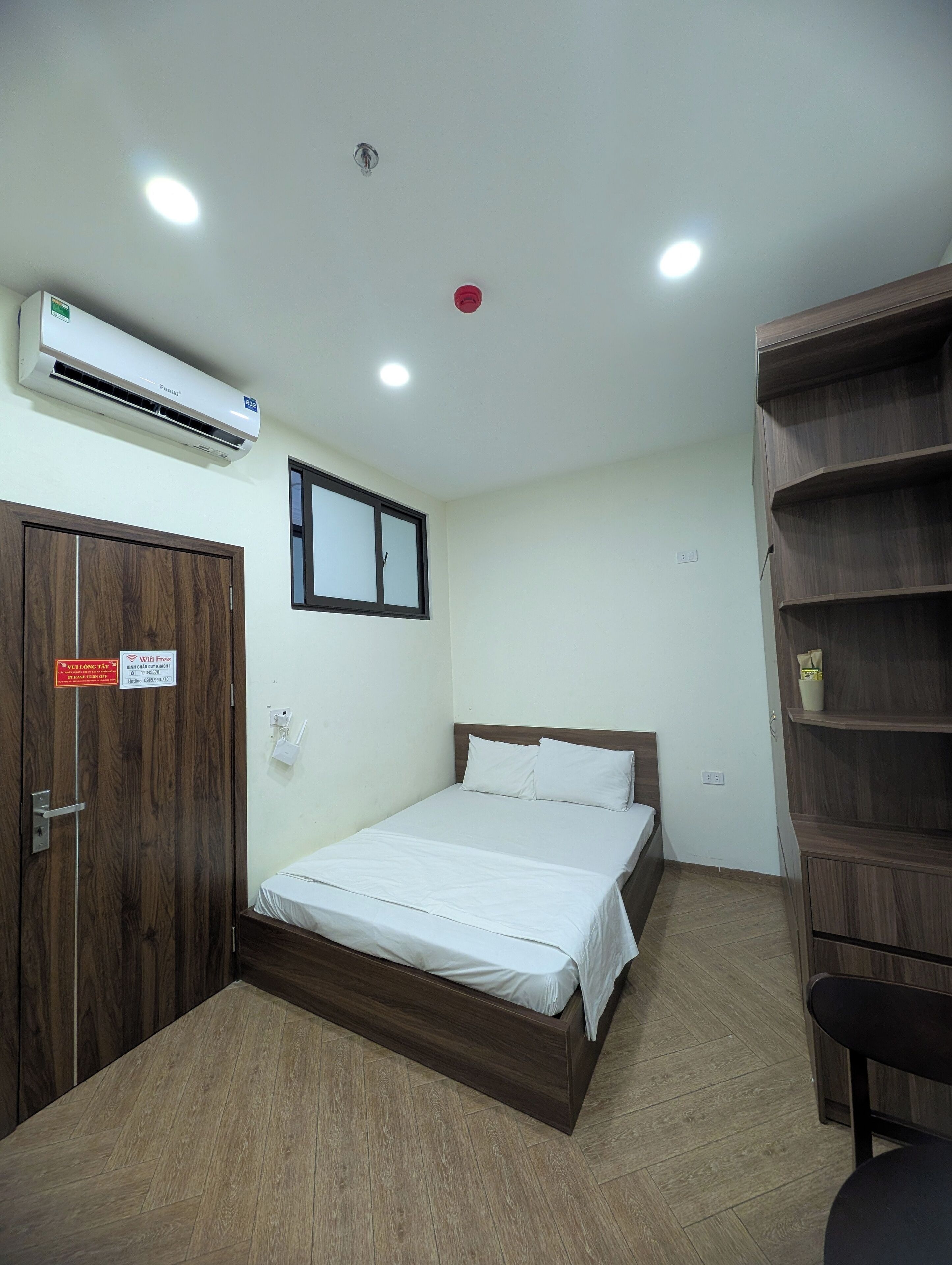 A hotel room with a bed, wardrobe, and built-in shelves.