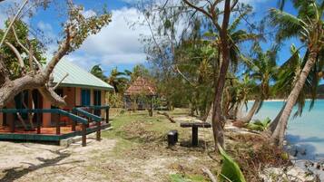A beachside property with a thatched-roof structure, a wooden deck, and a view of the ocean.