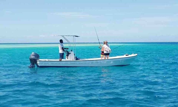 A small boat on calm blue water. - Long Beach Escape (Matathawa Island)