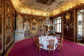An opulent room with ornate gold-framed mirrors, a chandelier, and a round table set for dining. - Schloss Leopoldskron Meierhof (Salzburg)