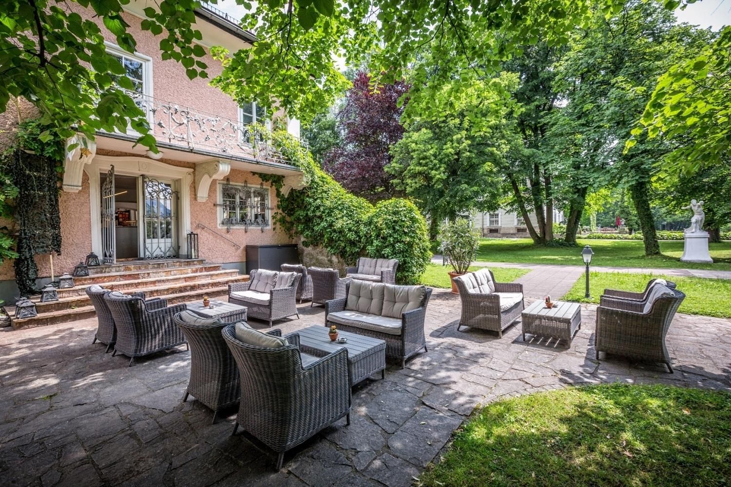 An outdoor patio with wicker furniture, a stone pathway, and a building with a balcony.