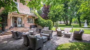 An outdoor patio with wicker furniture, a stone pathway, and a building with a balcony.