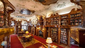 Eine prächtige Bibliothek mit aufwendigen Holzschnitzereien, Bücherregalen, einem Kamin und einer Chandelier.