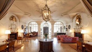 Eine geräumige Lobby mit einem prächtigen Kronleuchter, stilvollem Mobiliar und hohen Bogenfenstern.