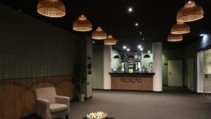 A reception area with a reception desk, a chair, a table with a decorative bowl, and hanging pendant lights. - Albufeira Lounge Hotel (Albufeira)
