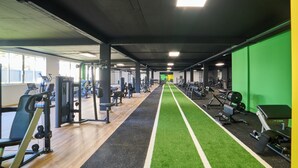 A gym with exercise equipment, a green turf running track, and a weightlifting area. - Albufeira Lounge Hotel (Albufeira)