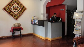 A reception area with a desk, a coat rack, and a wall-mounted decorative piece.