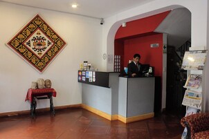 Un área de recepción con un mostrador, un perchero y un adorno en la pared.