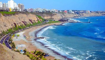 Un paisaje costero con playa, acantilados y un faro.