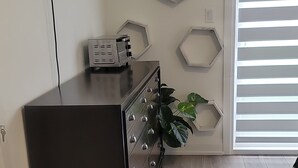 A room with a dark wooden cabinet, a flat-screen TV mounted on the wall, and hexagonal shelves. - Modern Suite Near Hamilton Airport (Hamilton)
