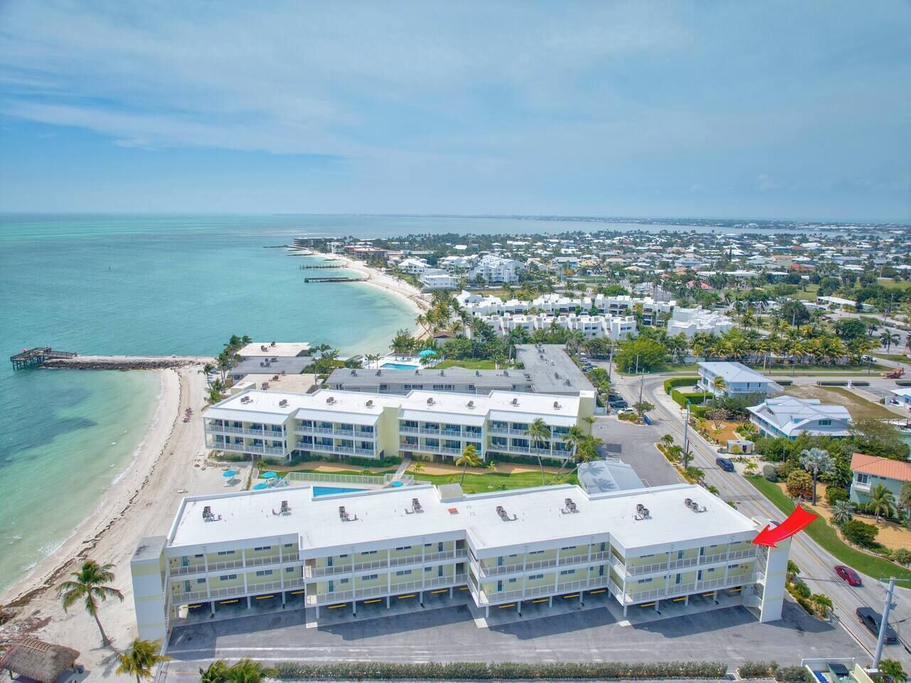 Un hotel fronte spiaggia con diversi edifici, un molo e una vista aperta sull'oceano.