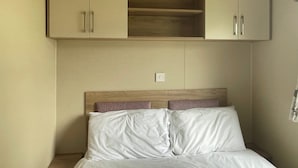 Een slaapkamer met een bed, twee kasten en een houten hoofdbord.