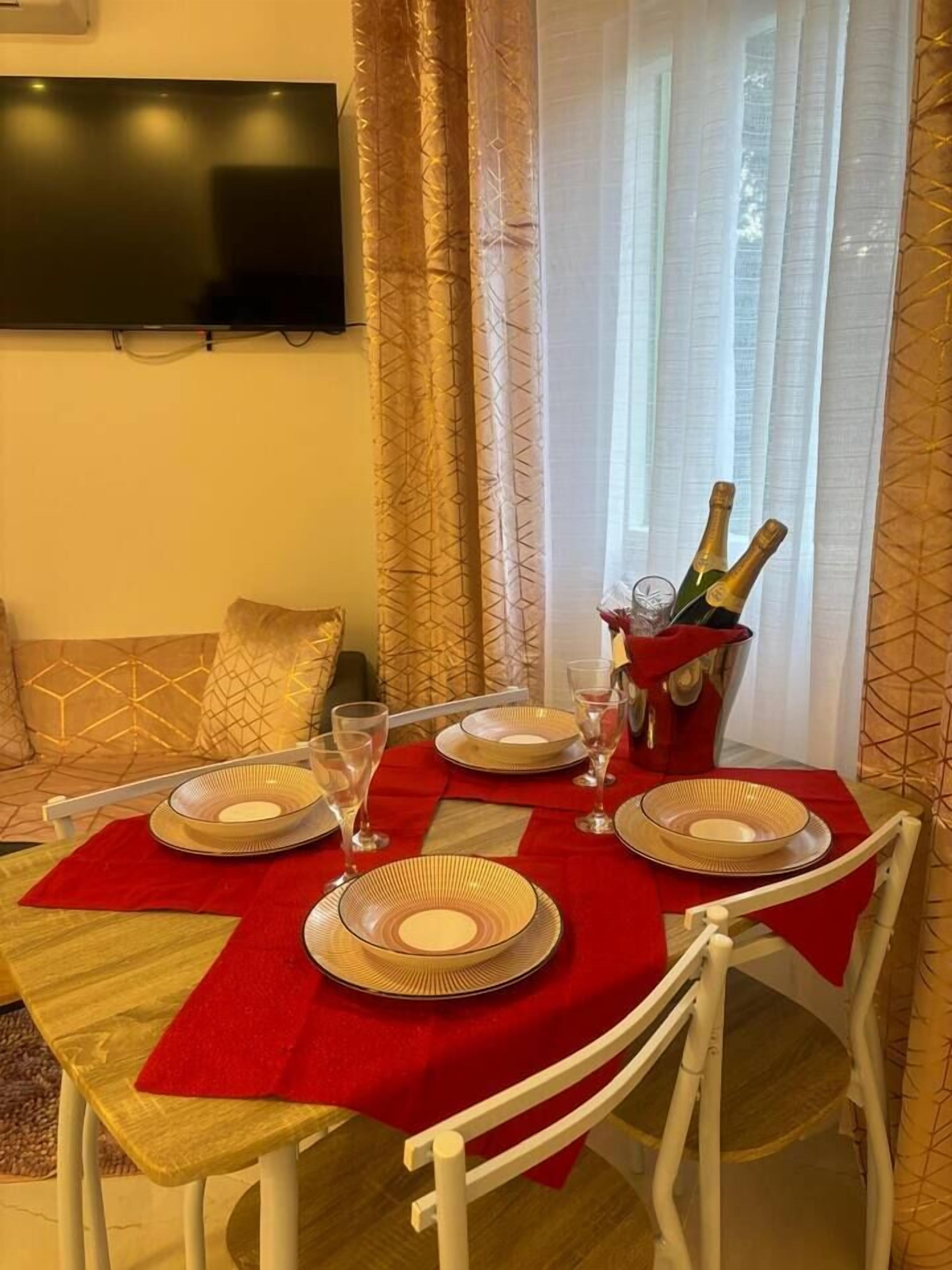 A dining table set with plates, glasses, and a bottle of champagne.