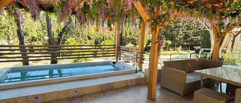 A covered outdoor area with a pool, wooden pergola, and seating.
