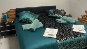 A bedroom with a bed, a nightstand, a wall-mounted air conditioner, and a window. - Aimee Tahiti - Loft. (Sanary-sur-Mer)