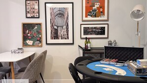 A room with a blackjack table, framed artwork on the walls, and a lamp. - Suite Near WEM: Game Room & Kitchen (Edmonton)
