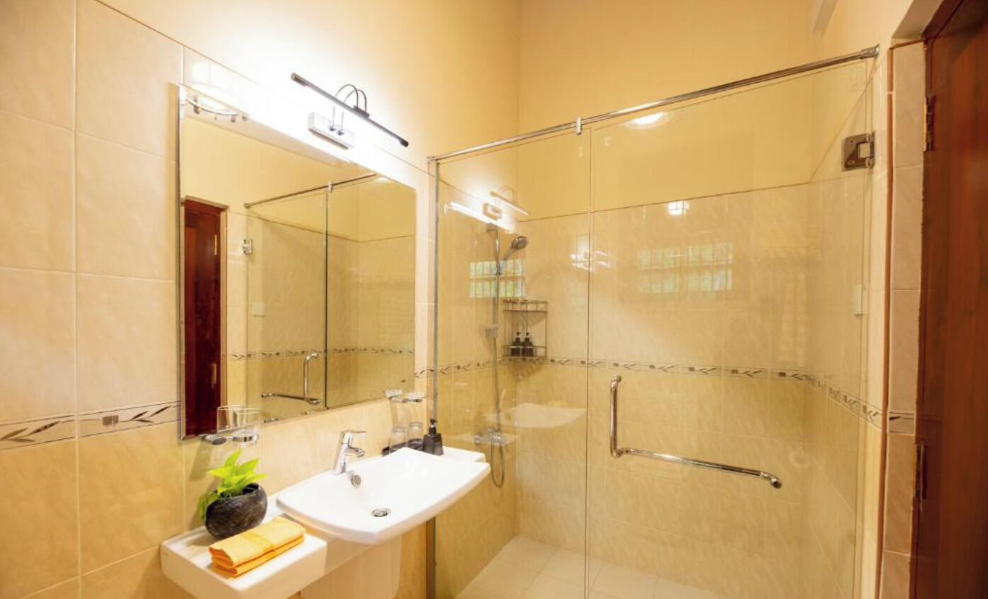 Un baño moderno con cabina de ducha de vidrio, lavamanos con espejo y un perchero para toallas.