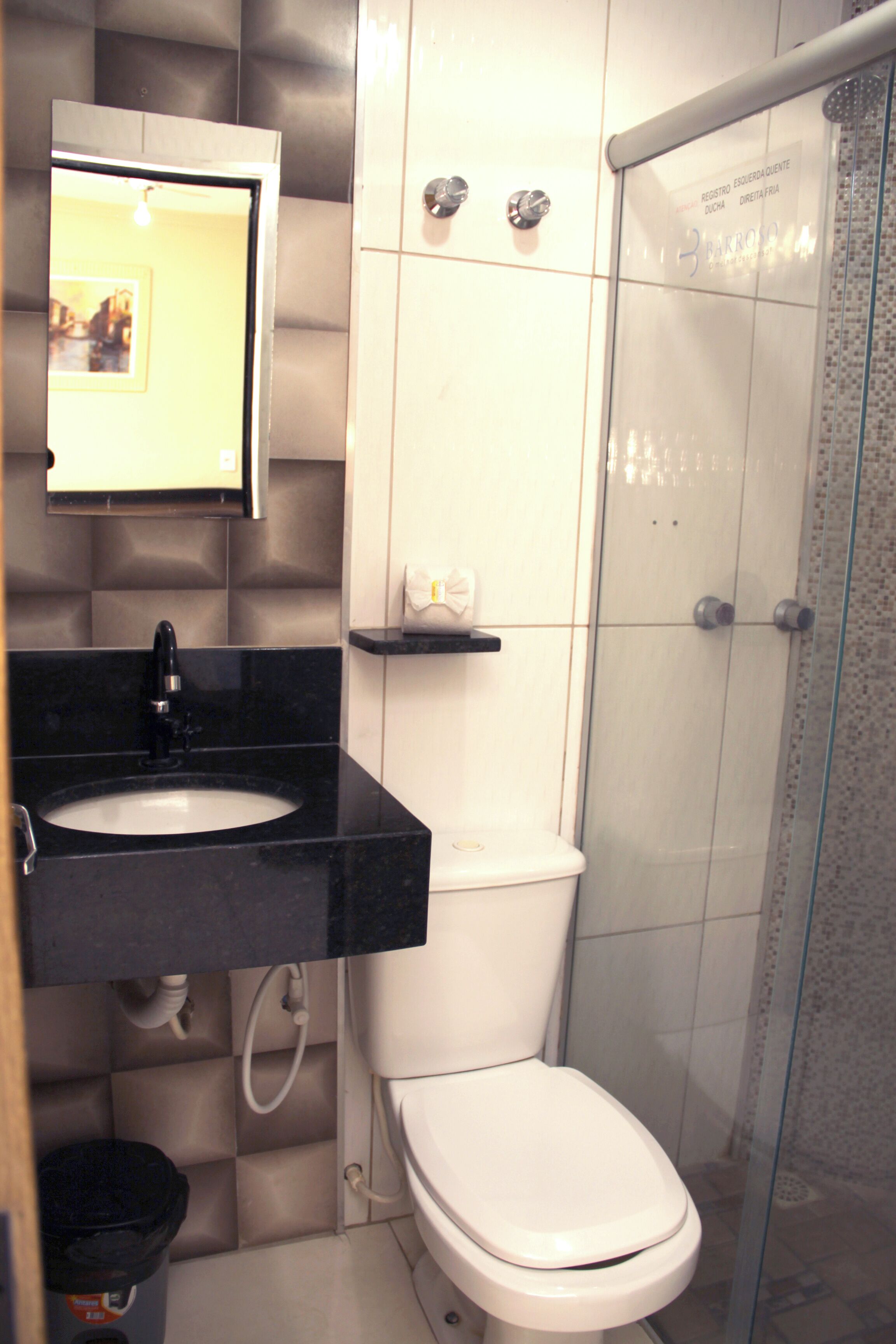 Un baño con un lavamanos negro, inodoro blanco y cabina de ducha con mampara de vidrio.