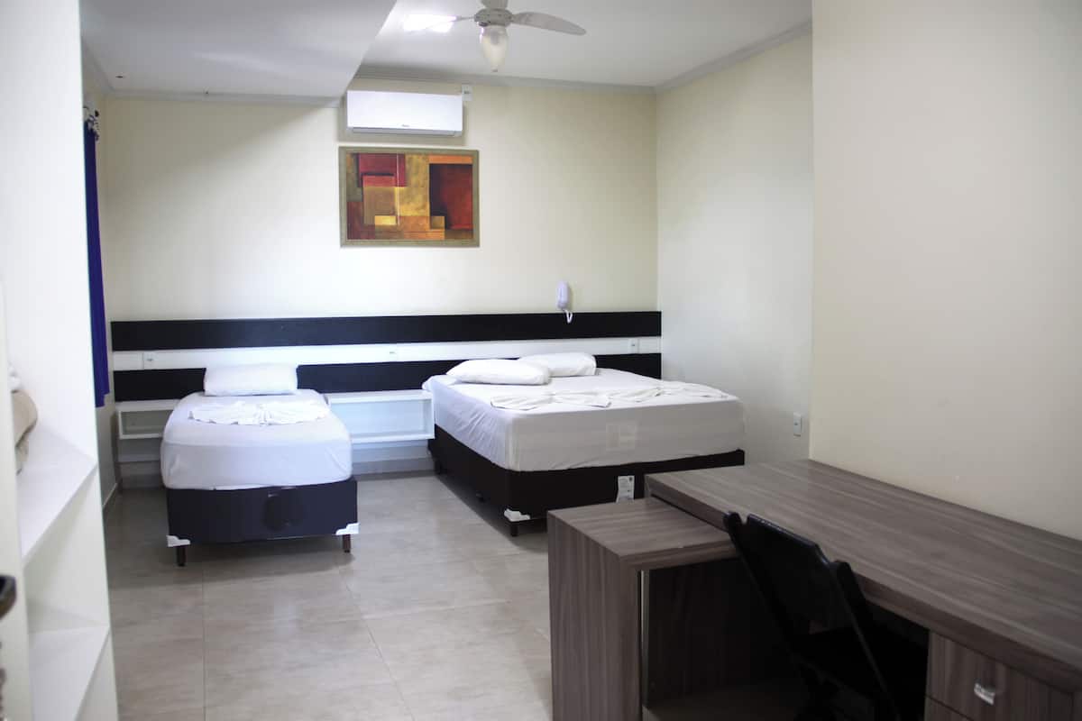 Une chambre d’hôtel avec deux lits, un bureau et un ventilateur de plafond.