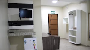 A hotel room with a television mounted on the wall, a minibar, a wardrobe, and a bed. - Hotel Barroso (Pirapora)