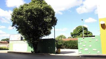 Um edifício verde com uma placa indicando 'Estacionamiento' e uma grande árvore em frente.