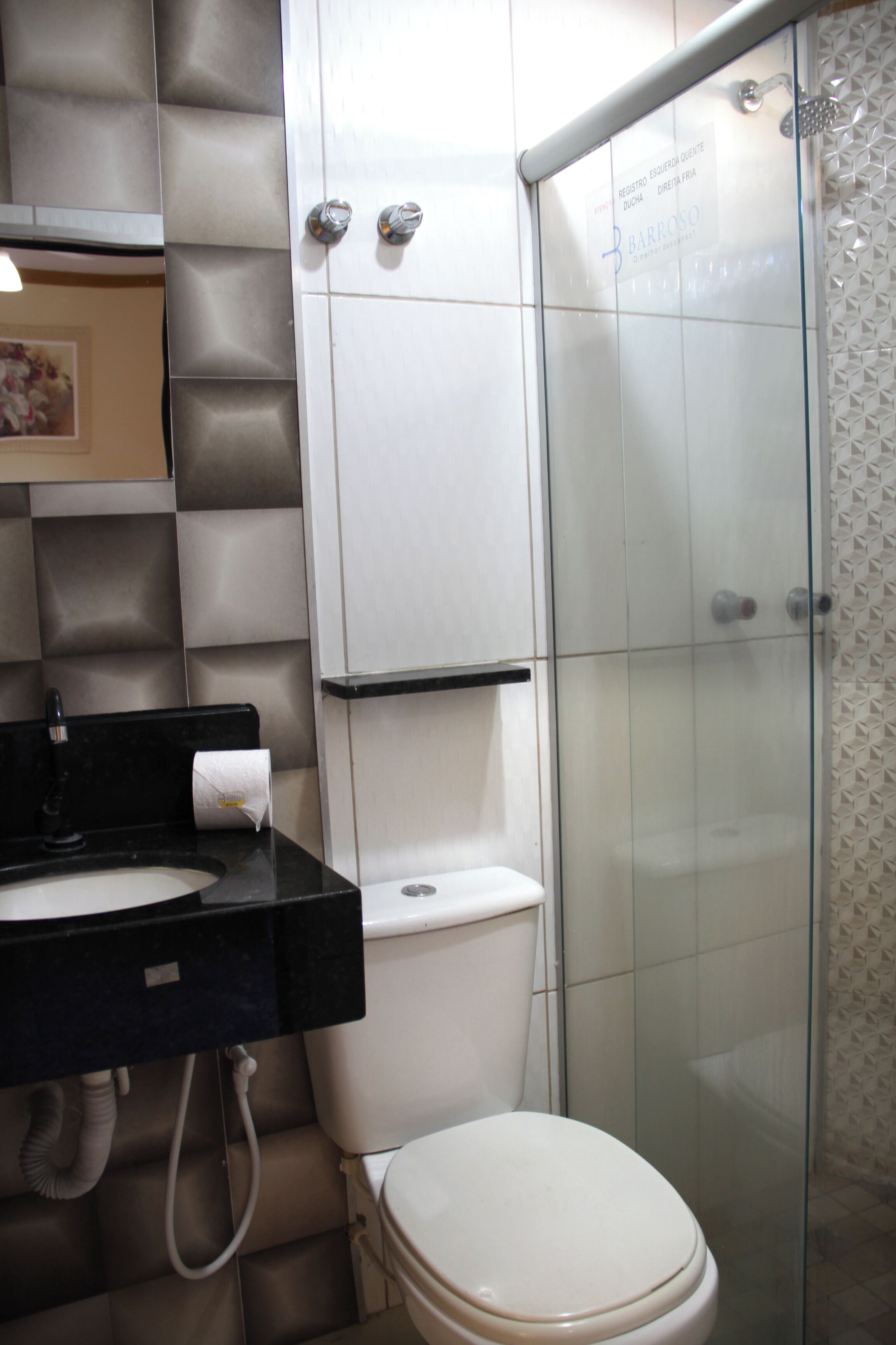 A bathroom with a toilet, sink, and glass shower enclosure.