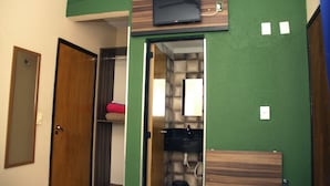 A bathroom with a green wall, a wooden vanity, a mirror, a sink, and a toilet. - Hotel Barroso (Pirapora)