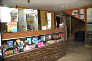 Un espace d’accueil avec un comptoir où sont exposés divers produits, un congélateur et un escalier menant à l’étage.