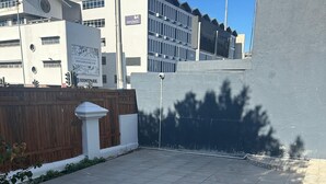 A courtyard with tiled flooring, a wooden fence, and a white column. - V & A Backpackers (Western Cape)