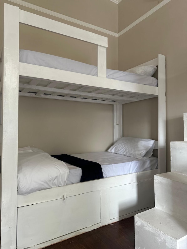 A bunk bed with a lower bunk and a single bed, both with white bedding. There is a small drawer under the lower bunk. - V & A Backpackers (Western Cape)