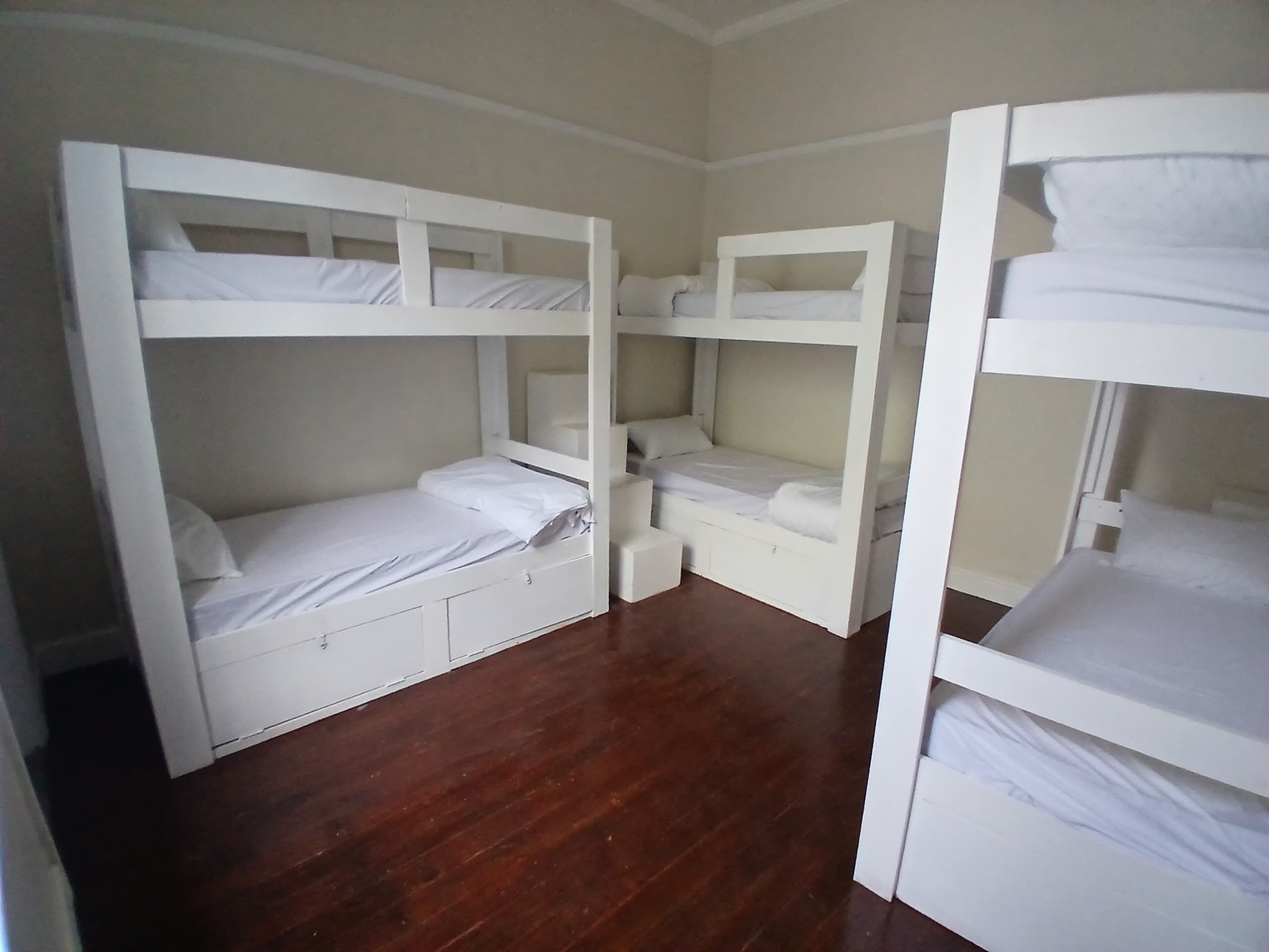 Ein Zimmer mit zwei Etagenbetten, Holzboden und weißen Wänden.