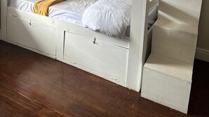 A bunk bed with a lower bunk and a storage drawer, white bedding, and a wooden floor. - V & A Backpackers (Western Cape)