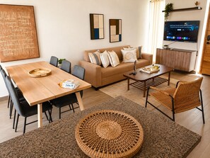Un salon moderne avec une table à manger en bois, un canapé et un téléviseur.
