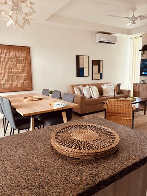 A modern living room with a dining area, featuring a sofa, chairs, a coffee table, and a TV. - Duplex House Pool and Beaches Nearby (Bávaro)