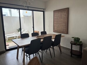 Un coin repas avec une table en bois, des chaises noires et une grande fenêtre.