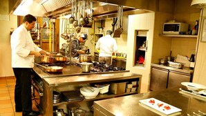 Une cuisine professionnelle équipée d’appareils en acier inoxydable, où des chefs préparent des plats, et où l’on trouve une variété d’ustensiles et de casseroles.