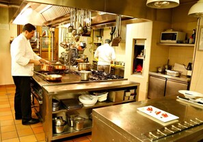 A professional kitchen with stainless steel appliances, chefs preparing food, and a variety of cooking utensils and pots. - La Locanda Di Bagnara (Bagnara di Romagna)