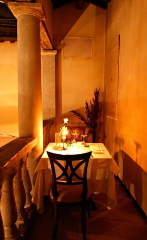 A table set for two with a candle, glasses, and a vase of flowers. - La Locanda Di Bagnara (Bagnara di Romagna)