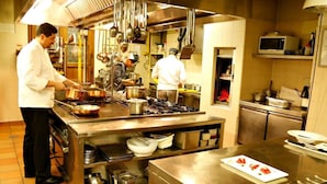 A professional kitchen with stainless steel appliances, chefs preparing food, and a variety of cooking utensils and pots. - La Locanda Di Bagnara (Bagnara di Romagna)