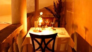 A table set for two with a candle, glasses, and a vase of flowers. - La Locanda Di Bagnara (Bagnara di Romagna)