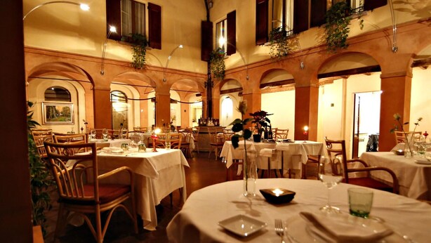 Un restaurant avec des tables rondes, des nappes blanches et des chaises en bois.