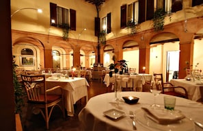 A restaurant with round tables, white tablecloths, and wooden chairs. - La Locanda Di Bagnara (Bagnara di Romagna)