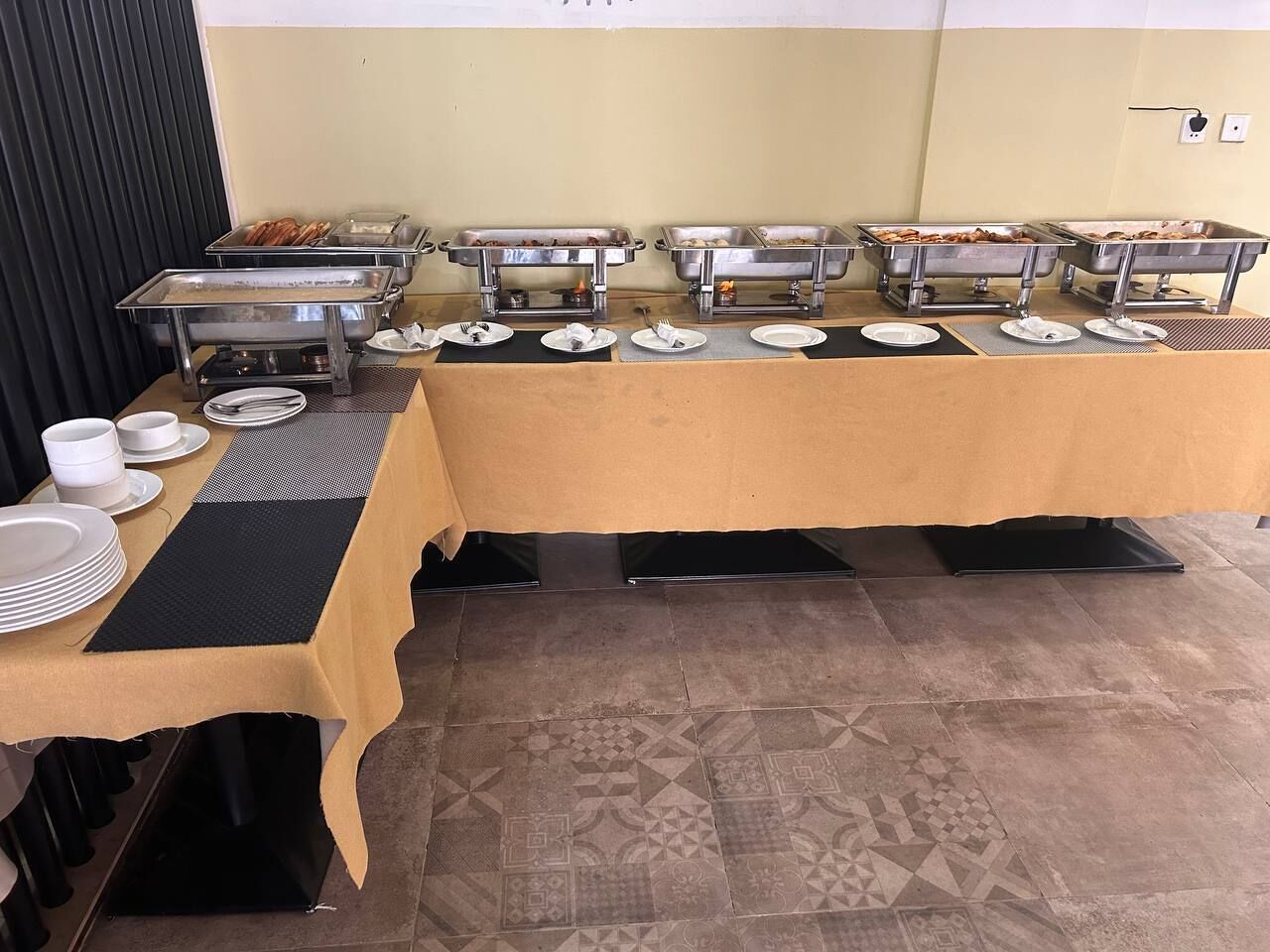 Uma mesa de buffet com várias estações de serviço e uma mesa com pratos e tigelas.