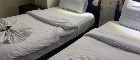 Two single beds with white linens and decorative towels.