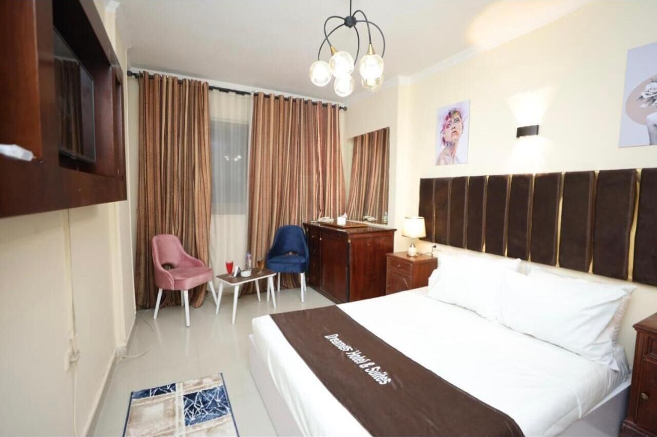 Ein Hotelzimmer mit einem großen Bett, einem Schreibtisch, einem Sessel, einem Fernseher und Vorhängen.