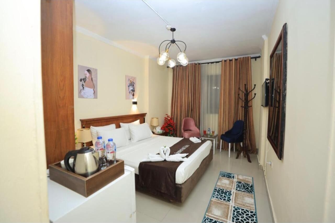 Ein Hotelzimmer mit Bett, Nachttisch, Lampe, Stuhl und einem kleinen Tisch mit Tablett.