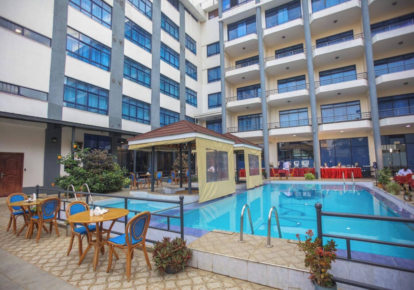 A hotel atrium with a swimming pool, outdoor seating area, and multiple balconies.